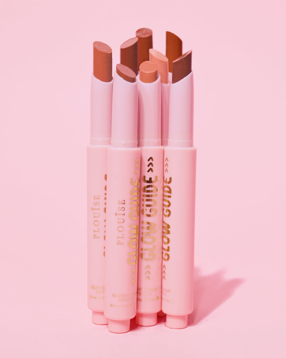Kuva, jossa P.Louise Glow Guide Glossy Lipstick Balsm -huulipunabalsami kokonaisuudessaan ilman huulia, joka näyttää värivalikoiman vaaleanpunaisella taustalla