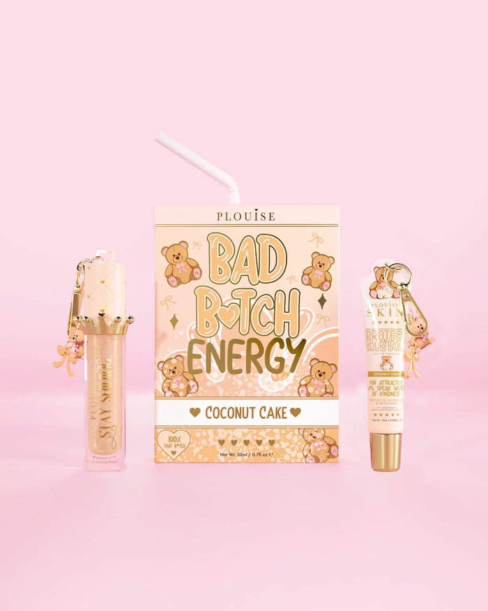 P.Louise Teddy Glitter Bad Bitch Energy Lip Duo kookoskakun tuoksussa, jossa huulihoitoaine ja huuliöljy vaaleanpunaista taustaa vasten