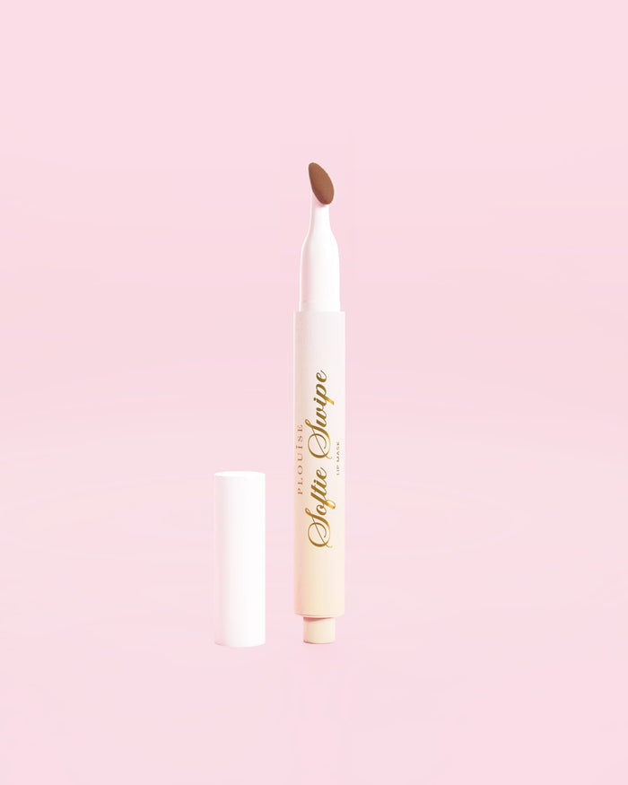 Kuva P.Louise Softie Swipe Swipe Tinted Lip Maskista Soft Launchissa vaaleanpunaista taustaa vasten