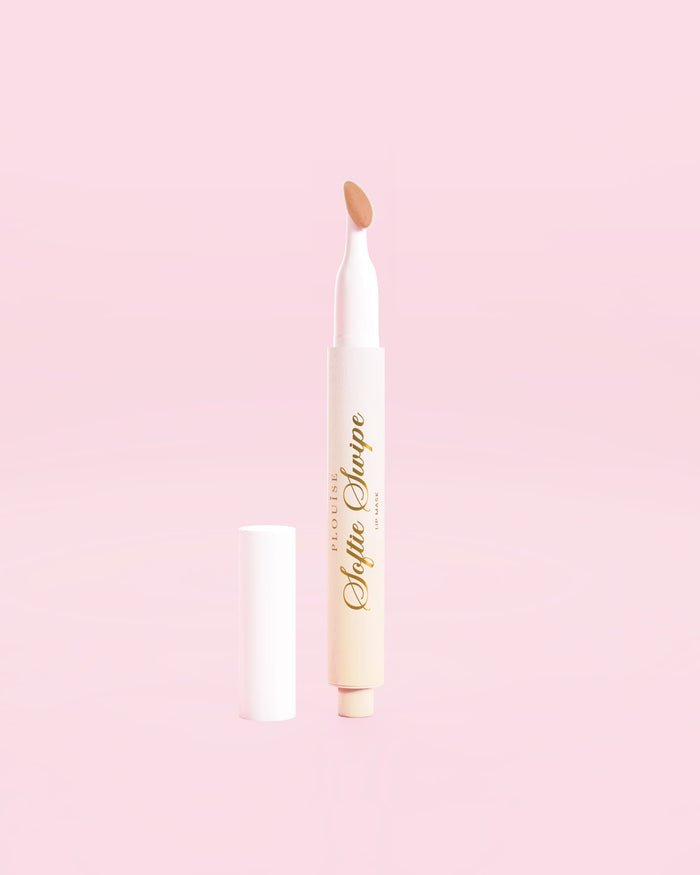 Kuvassa P.Louise Softie Swipe Tinted Lip Mask Barely There -sävyssä vaaleanpunaista taustaa vasten