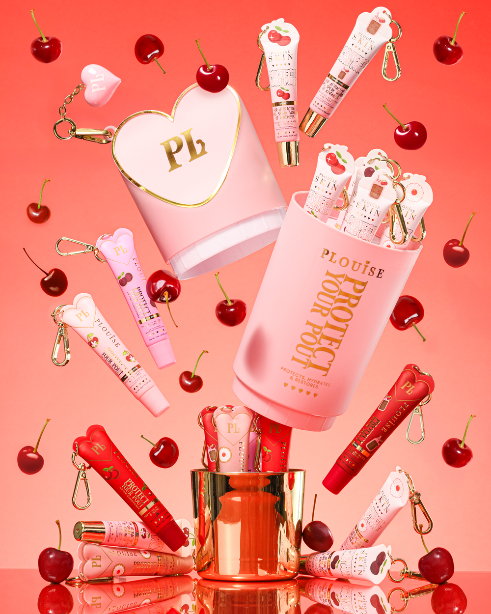 Pink XL Protect Your Pout -lahjasetti, joka avataan kirsikoiden ja vaaleanpunaisten ja punaisten huulihoitoaineiden ympäröimänä vaaleanpunaisella taustalla