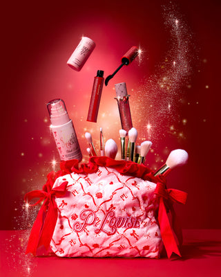 Vaaleanpunainen joulu P.Louise meikkilaukku, jossa on punainen juhlava kuviointi ja meikkituotteet tulevat esiin punaisella taustalla kullan kimaltelemalla