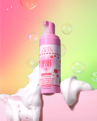 Pink foaming bottle of P.Louise Shake It Off Face Cleanservwith heart design on a colourful background with bubbles