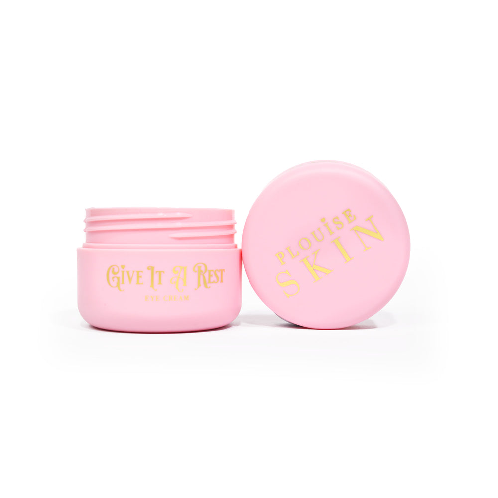A pink open jar of P.Louise Give It A Rest Eye Cream showing the lid and jar from the sidewith the branding and product name on the jar in gold writing