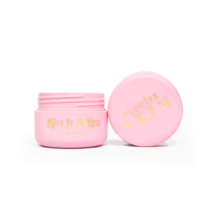 Vaaleanpunainen avoin purkki P.Louise Give It A Rest Eye Cream -silmävoidetta, jonka kansi ja purkki näkyvät sivulta ja purkin tuotemerkki ja tuotteen nimi kullalla kirjoitettuna